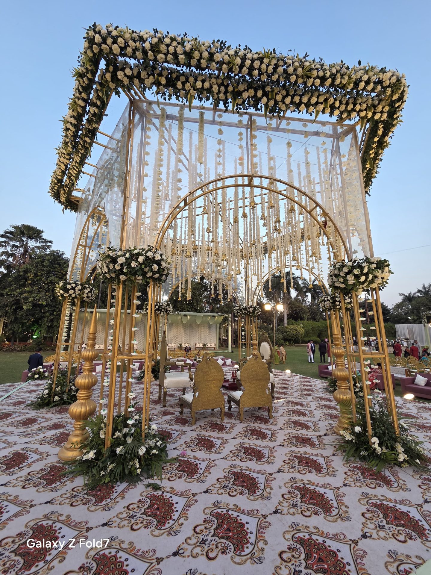 Gold cube mandap with rose garland canopy at dusk