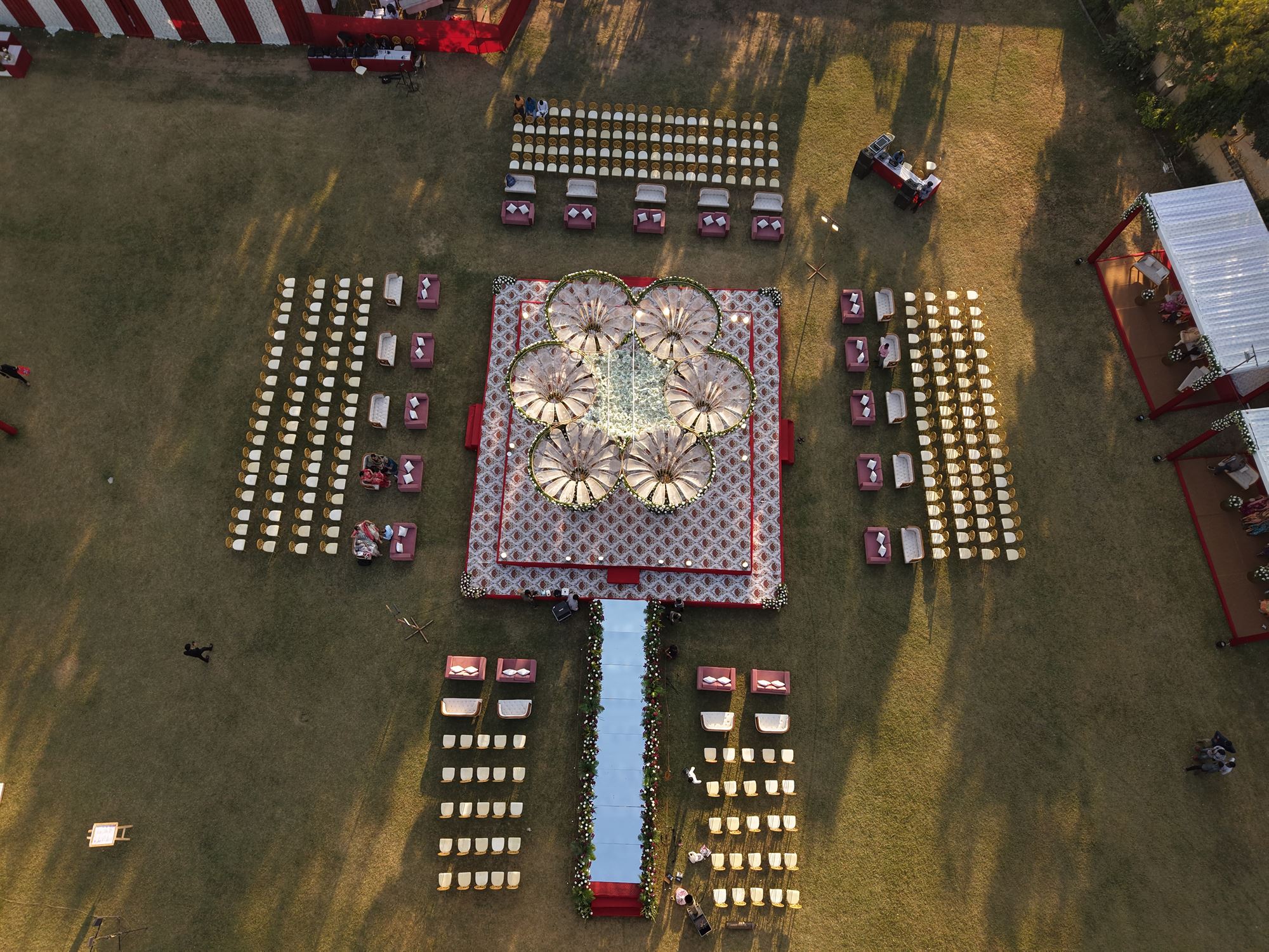 Top-down aerial view of a flower-shaped wedding mandap with mirrored aisle and guest seating
