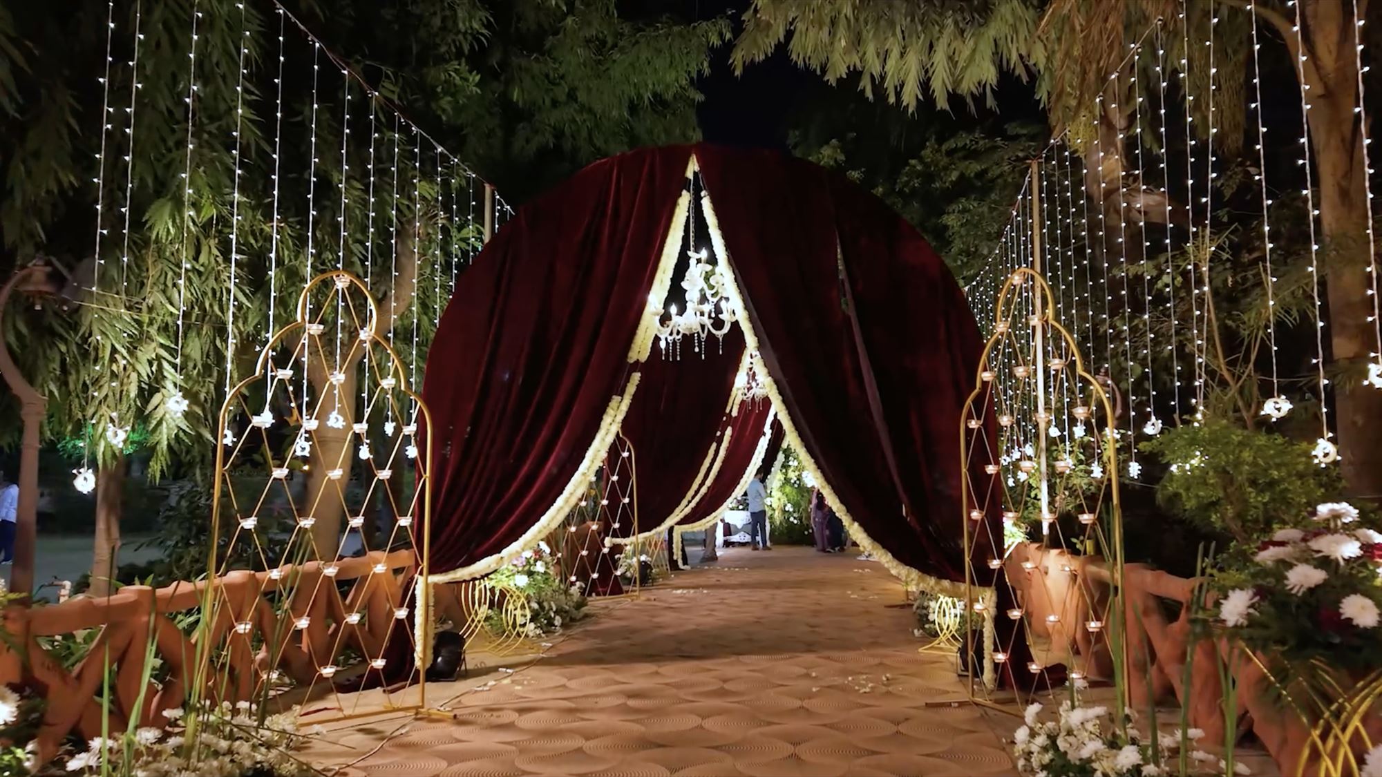 Circular velvet arch entrance with fairy-light curtains and candle screens at night
